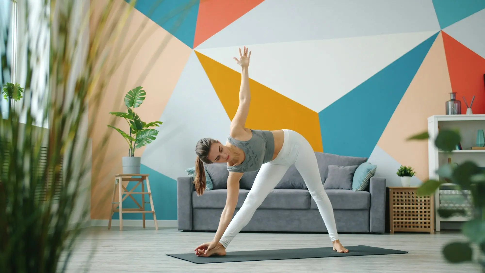 Pratiquante de yoga en posture du triangle sur un tapis, à la maison