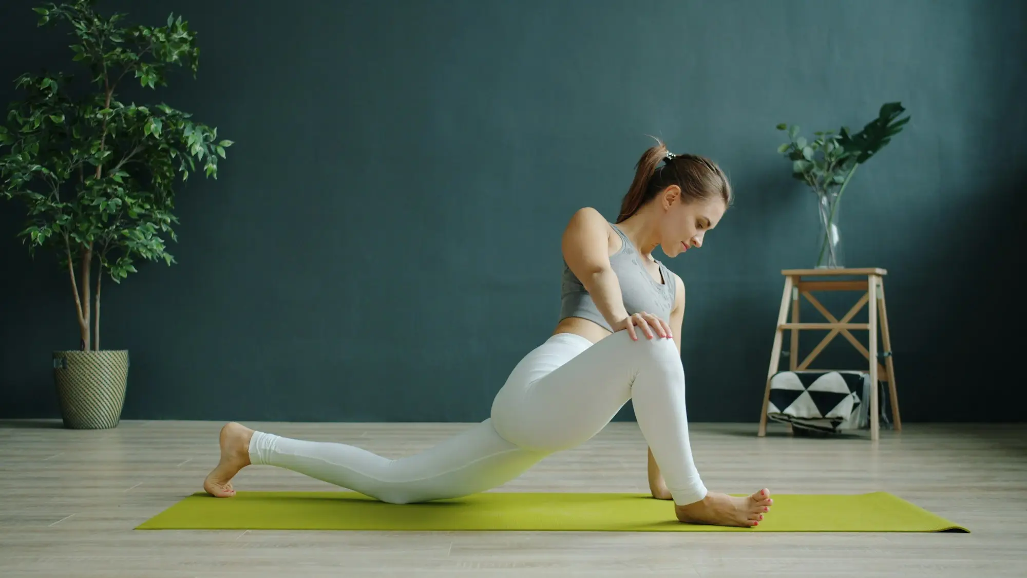 Femme en fente basse sur un tapis de yoga dans un salon lumineux